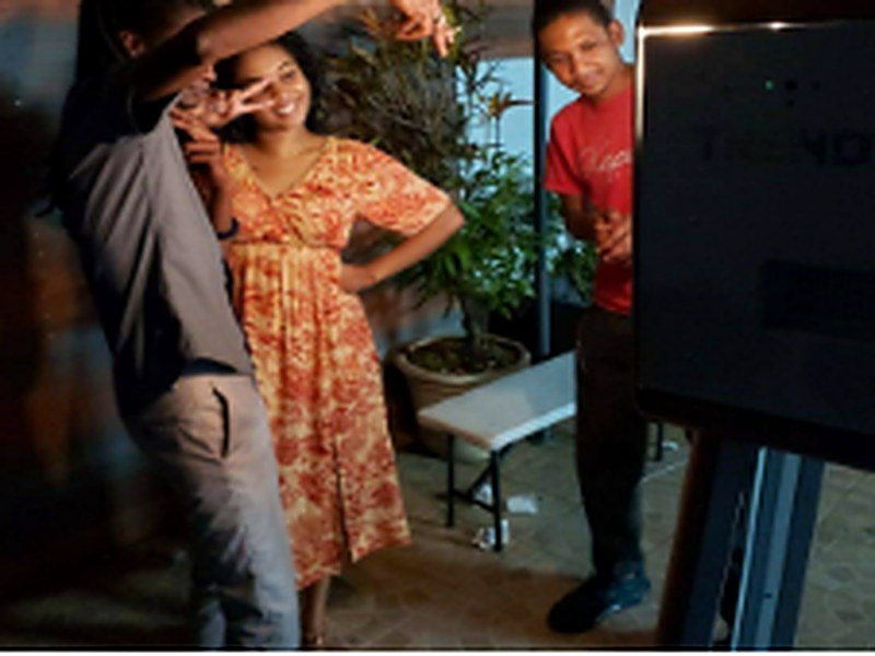 Amis riant ensemble devant le photobooth pendant une soirée